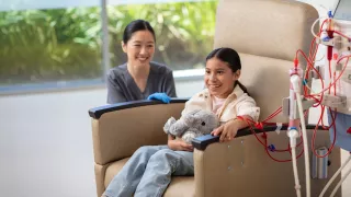 Young patient receives HD therapy sitting in a chair with a clinician beside her