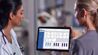 Two female healthcare professionals look at data on an tablet