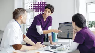 Nurse pointing at a screen in a meeting