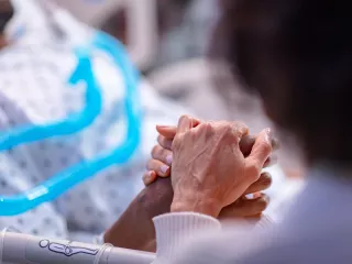 Two people holding hands in a hospital bed