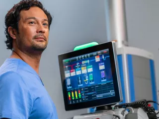 A healthcare professional stands in front of a PrisMax system