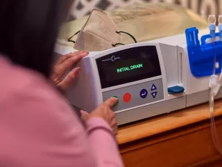 A woman interacts with the Homechoice Claria on her bedside table.